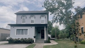 A two-story house with a front porch, a small front yard, and a driveway.