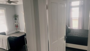 A bedroom with a bed, a bedside table, a chair, a bookshelf, and a door.