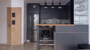 A modern kitchen with a built-in refrigerator, a wooden door, and a bar area with stools.
