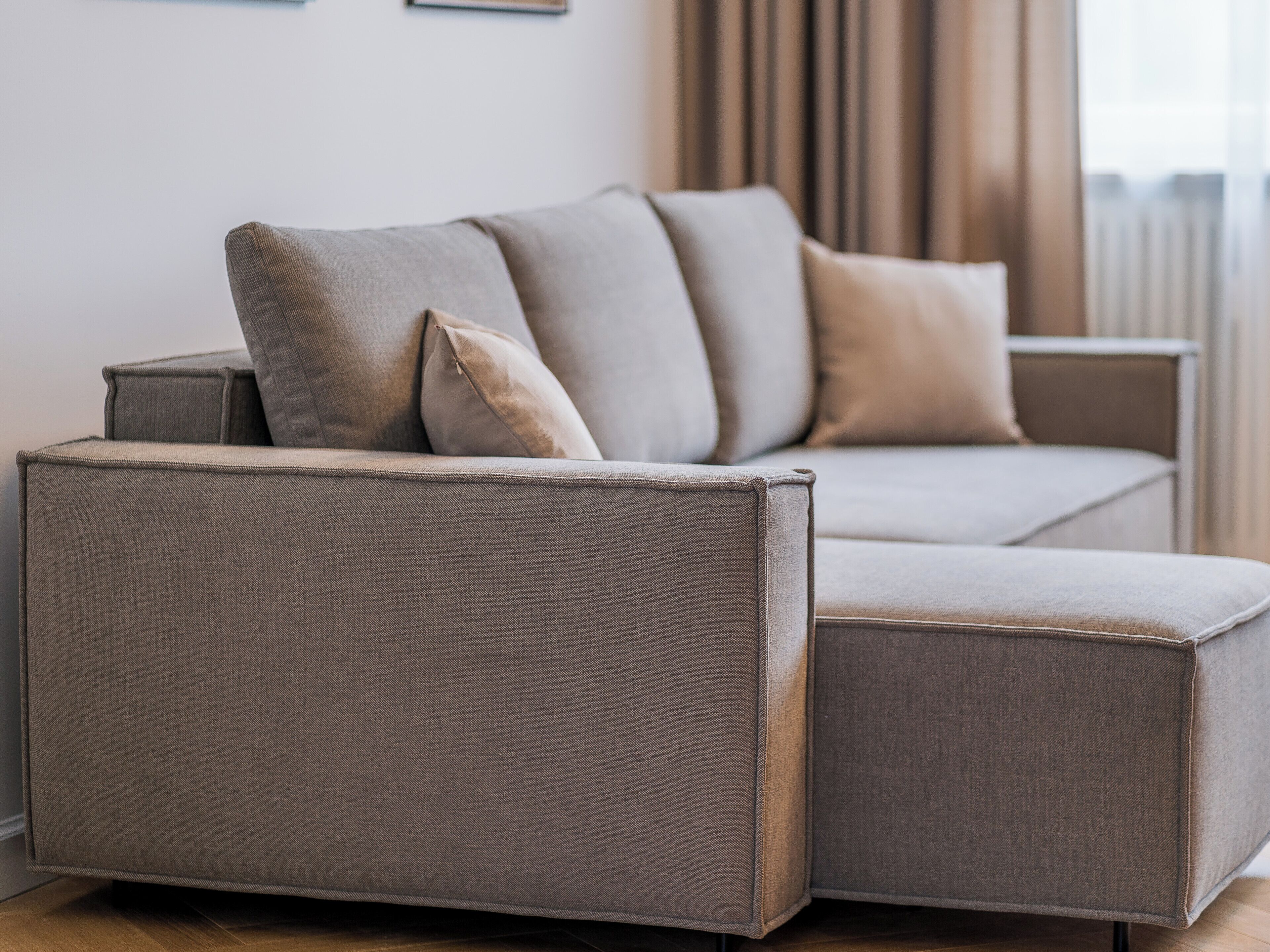 Um sofá modular moderno com tecido texturizado, posicionado em um ambiente bem iluminado e com paleta de cores neutras.