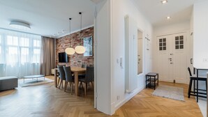 A modern kitchen with a brick wall backsplash, wooden flooring, and pendant lighting. - Kochanowskiego Luxury Apartment (Poznań)