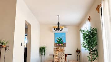 Une pièce spacieuse comprenant un coin repas, un luminaire au plafond et un tableau représentant un cactus.
