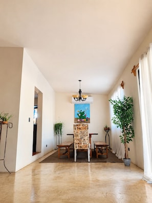 A spacious room with a dining area, a ceiling light, and a cactus painting.