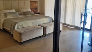 Une chambre à coucher avec un lit, un banc, un ventilateur de plafond et une fenêtre avec des rideaux.