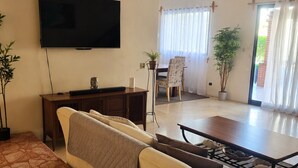 Un salon comprenant un canapé, une table basse, un téléviseur et un coin repas avec une table et des chaises.