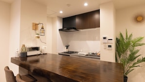 Una cucina moderna con un piano di lavoro in legno scuro, elettrodomestici integrati e una cappa nera sopra il fornello.