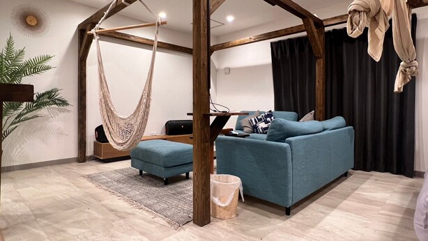 Un soggiorno moderno con un'amaca, un divano blu e una struttura a soffitto in legno.