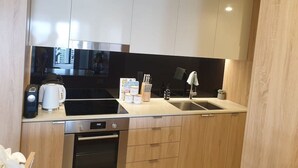 Une cuisine compacte équipée d’un four à micro-ondes, d’une cuisinière, d’un évier et de meubles de rangement modernes.