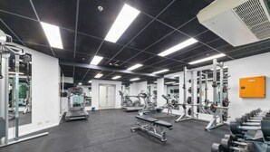 A gym with various exercise equipment, including treadmills, weight machines, and dumbbells.