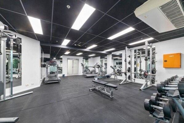 A gym with various exercise equipment, including treadmills, weight machines, and dumbbells.