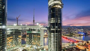 A modern high-rise building with a curved facade, surrounded by other high-rise structures and a river.