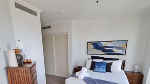 A bedroom with a bed, a dresser, a painting, and a door.