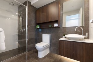 Une salle de bain moderne avec une douche à parois de verre, des toilettes blanches et un meuble-lavabo avec un évier et un miroir.