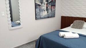 Un dormitorio con una cama, un espejo, un cuadro y una almohada.