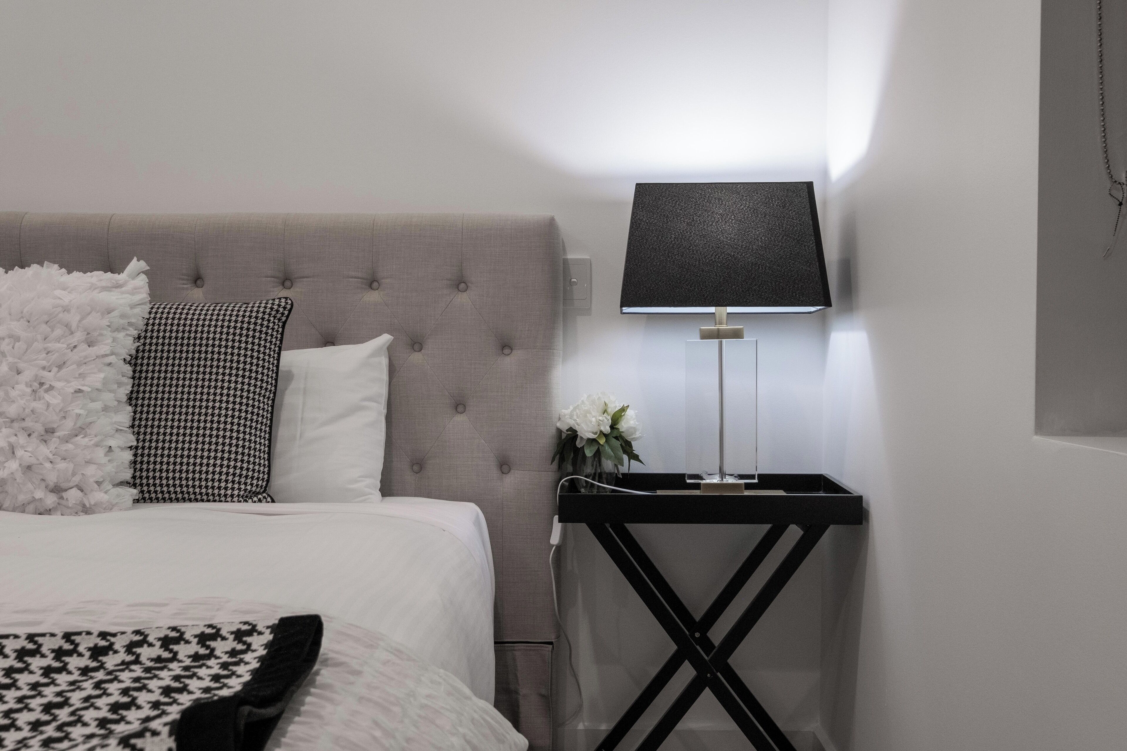 A neatly arranged bedroom with a bed, a bedside table with a lamp, and a decorative wall piece.
