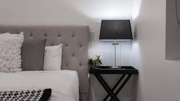 A neatly arranged bedroom with a bed, a bedside table with a lamp, and a decorative wall piece.