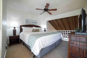 Una camera da letto con un letto, comodini, una ventola a soffitto, una cassettiera e vista sull'esterno.