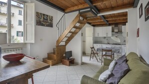 A modern apartment with a wooden staircase, a dining area, a kitchen, and a living room with a green sofa. - Angelico's Urban Loft (Firenze)