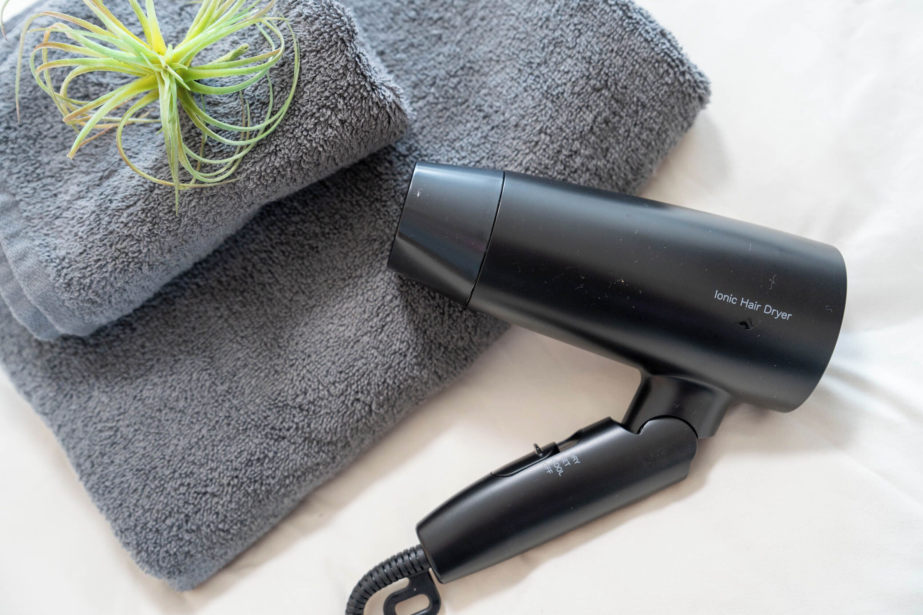 Un sèche-cheveux et des serviettes pliées sur un lit.