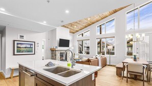 A modern kitchen with a large island, built-in appliances, and a dining area with a wooden table and chairs.