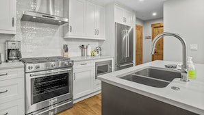 Una cucina moderna con mobili bianchi, elettrodomestici in acciaio inossidabile e una grande isola con lavello.