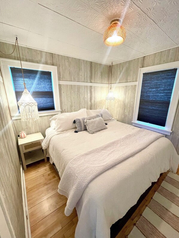 A bedroom with a large bed, two bedside tables, and a window with a view. - Adorable cottage in Frankfort, walkable to town and the beach! (Frankfort)