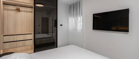 A modern hotel room with a bed, a wardrobe, a mirror, and a TV.