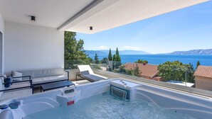 A balcony with a hot tub, a sofa, and a view of the sea and mountains. - Luxurious apartment in Novi Vinodolski with WiFi (Novi Vinodolski)