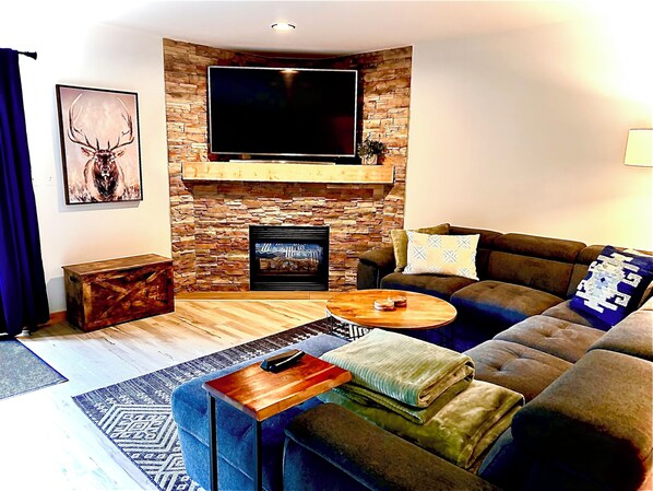 Una sala de estar moderna con chimenea de piedra, un televisor de pantalla plana, un sofá y una mesa de centro.