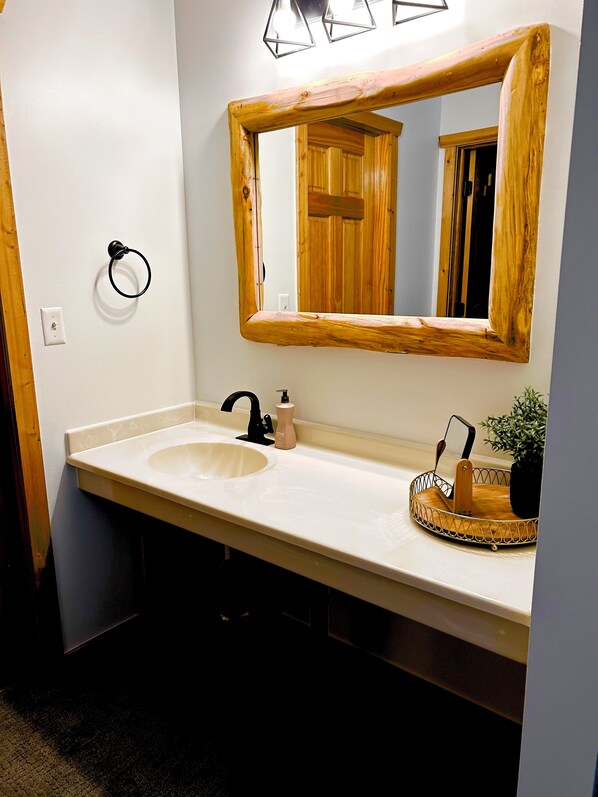 A bathroom with a white sink, a wooden-framed mirror, and a towel ring. - NEW !!! COZY , RUSTIC 2-bedroom townhome Near STARVED ROCK !!! (North Utica)