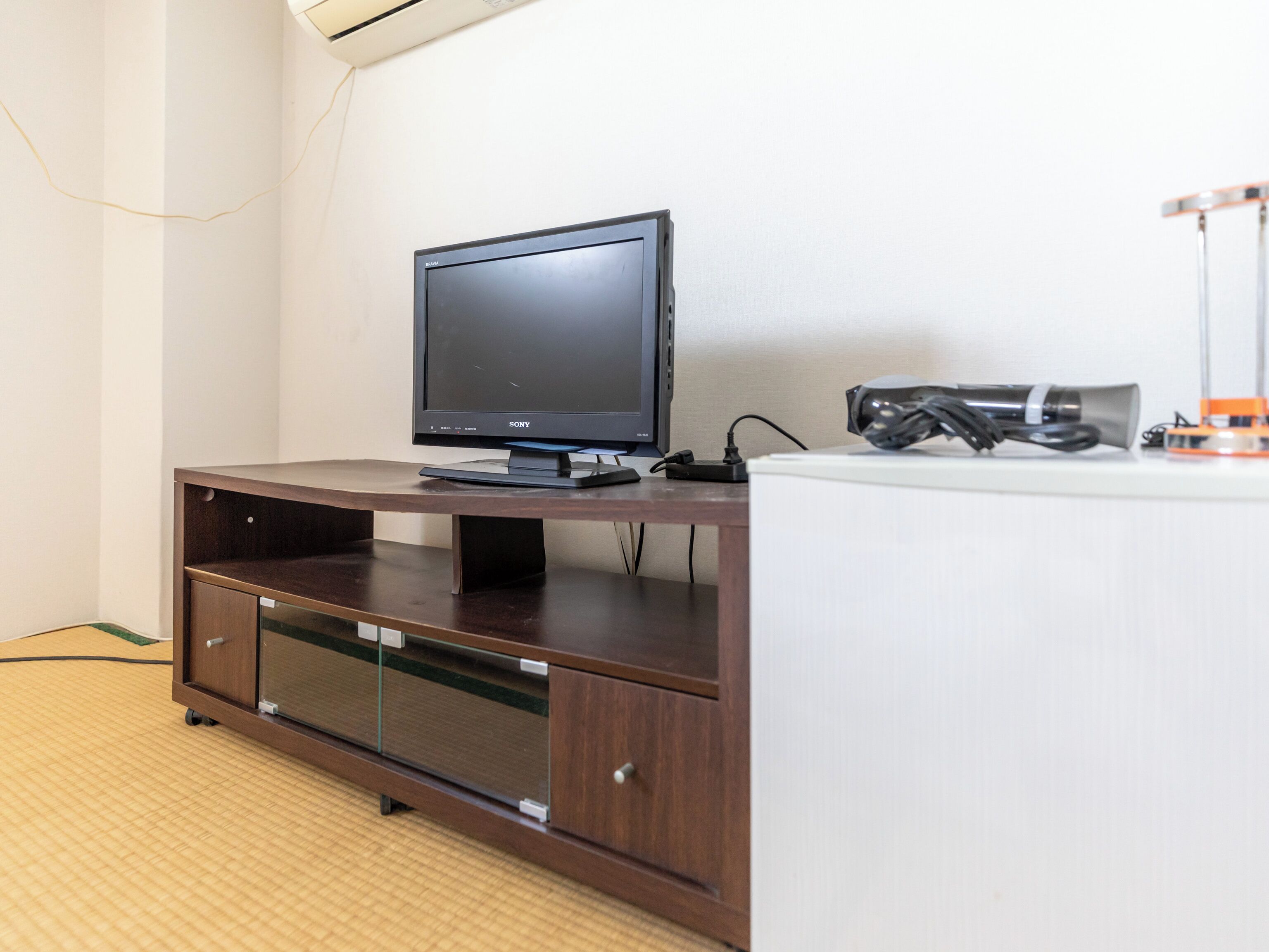 A modern entertainment unit with a flat-screen TV, a gaming console, and a small cabinet.