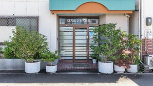 A building with a green awning and a sign in Japanese. There are potted plants in front of the entrance. - Tabist Hara Business Ryokan (Wakayama)