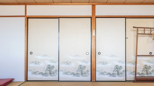 A traditional Japanese room with tatami flooring, sliding doors with nature-themed designs, and a wooden ladder. - Tabist Hara Business Ryokan (Wakayama)