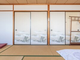 Una habitación japonesa tradicional con suelo de tatami, puertas correderas con motivos naturales y una escalera de madera.