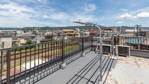 A rooftop with a metal railing overlooking a cityscape, including buildings and a railway track. - Tabist Hara Business Ryokan (Wakayama)