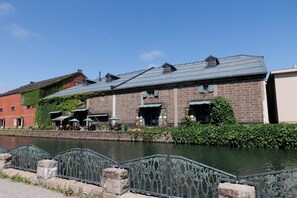 A riverside building with brick walls, green awnings, and outdoor seating. - aquamarine (Otaru)