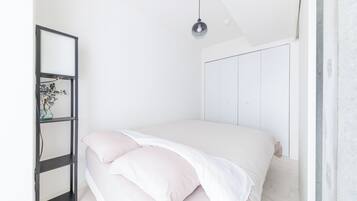A bedroom with a bed, a bedside table, a mirror, and a hanging light fixture.