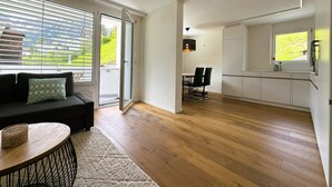 Um espaço de estar moderno com sofá, mesa de jantar e cozinha.