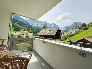 A balcony with a view of a mountain landscape, a table with chairs, and a railing. - Sunnmatt West Wohnung 933 Appartement/Fewo 5-Bettwohnung by Interhome (Engelberg)