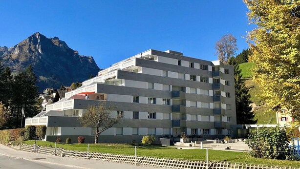 Um hotel de vários andares com design moderno, com varandas e vista para uma montanha.