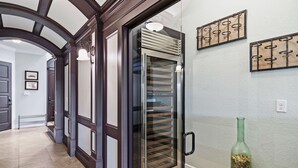 Ein Flur mit einer modernen Küchenzeile, einem Kühlschrank mit Glastür und einer dekorativen Flasche auf dem Boden.