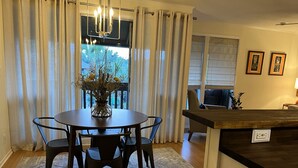 Un coin repas comprenant une table ronde, quatre chaises, un vase avec des fleurs et un lustre.
