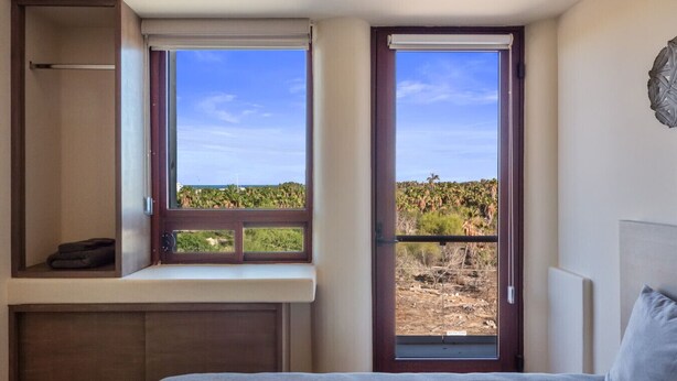 Ein Schlafzimmer mit einem Bett, einem Fenster und Blick auf eine Landschaft.