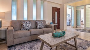 Ein Wohnzimmer mit einer Couch, einem Couchtisch und einer Tür zu einem anderen Raum.