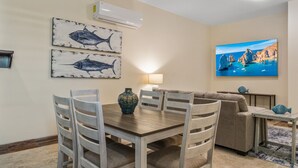 A dining area with a table and chairs, a sofa, a TV, and wall art. - Tormenta 202 3BR Second Floor San Jose del Cabo (San José del Cabo)