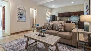 A living room with a sofa, coffee table, and a kitchen in the background. - Tormenta 202 3BR Second Floor San Jose del Cabo (San José del Cabo)