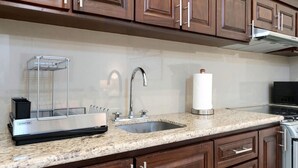 A kitchen with a granite countertop, stainless steel sink, and wooden cabinets. - Tormenta 101 3BR Ground Floor San Jose del Cabo (San José del Cabo)