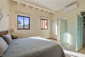 A bedroom with a bed, two windows, a nightstand, a lamp, and a closet with a sliding door.