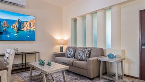 Una sala de estar con un sofá, una mesa de centro, un televisor, una lámpara y una pequeña mesa con una decoración de pez.