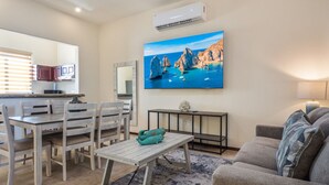 Una sala de estar con comedor, un televisor montado y una pequeña mesa con un florero.